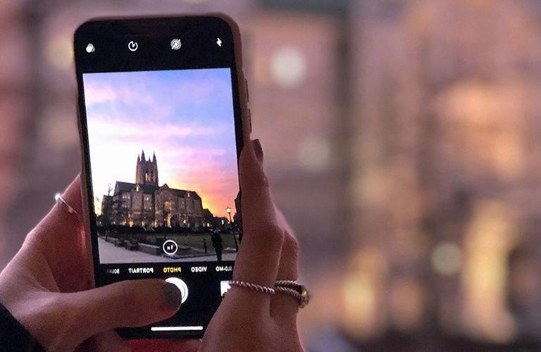 Student holding a cellphone to take a photo of Gasson Hall